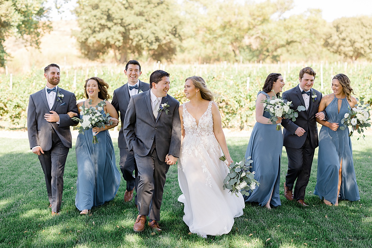 wedding party in dusty blue and gray walk with bride and groom shot by Hunter Hennes Photography