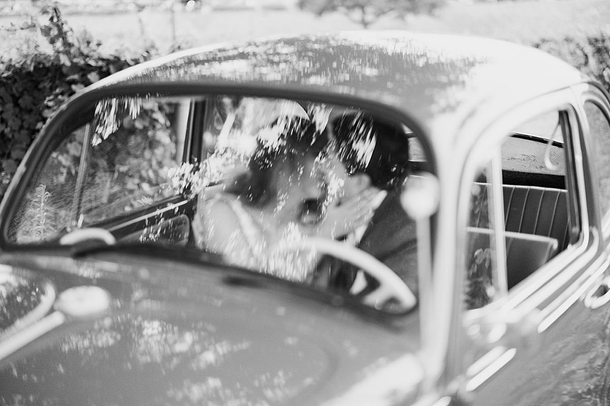 newlyweds kiss in front seat of volkswagen beetle after ceremony shot by destination wedding photographer