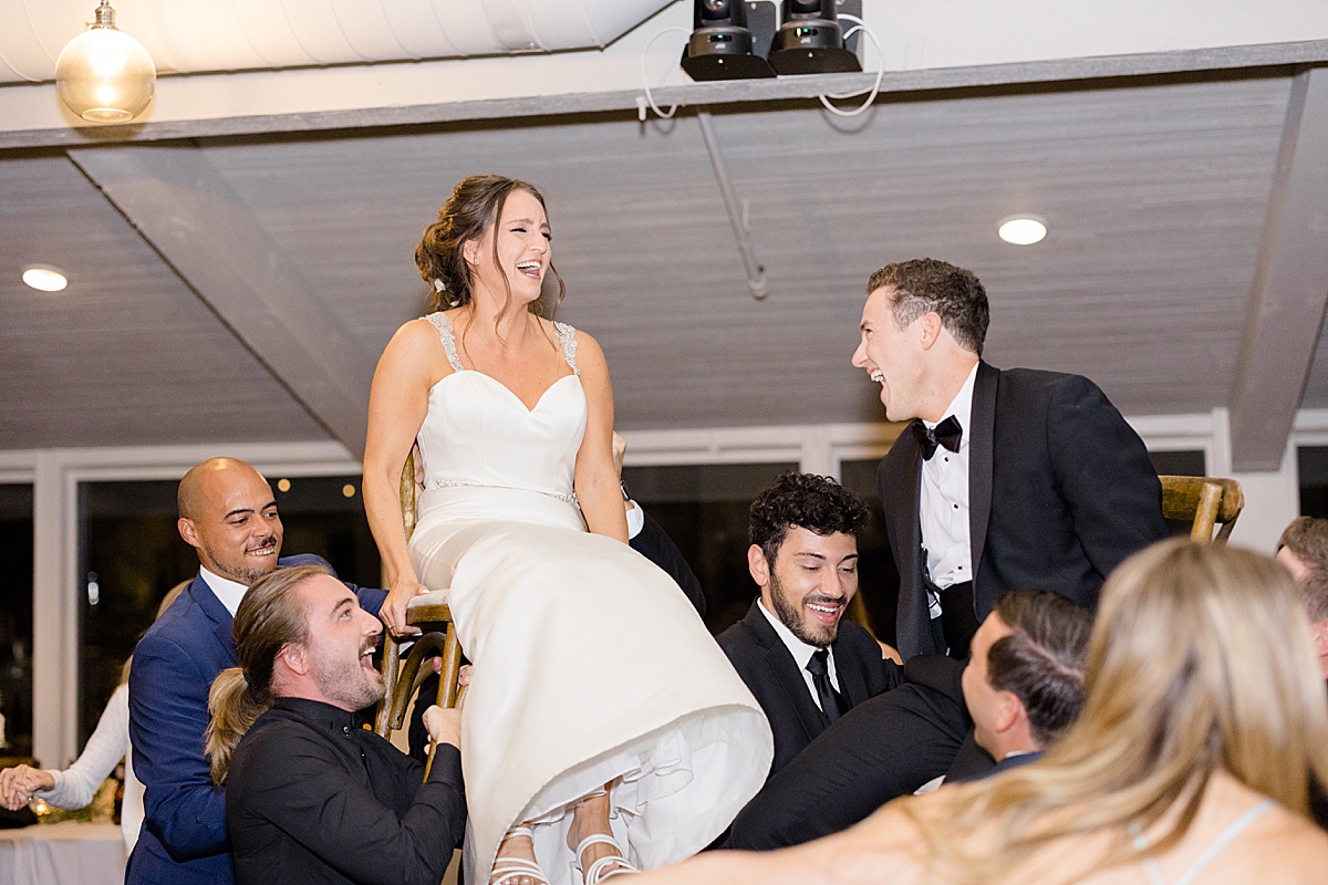 bride and groom are lifted on chairs by reception guests at jewish wedding shot by Destination wedding photographer
