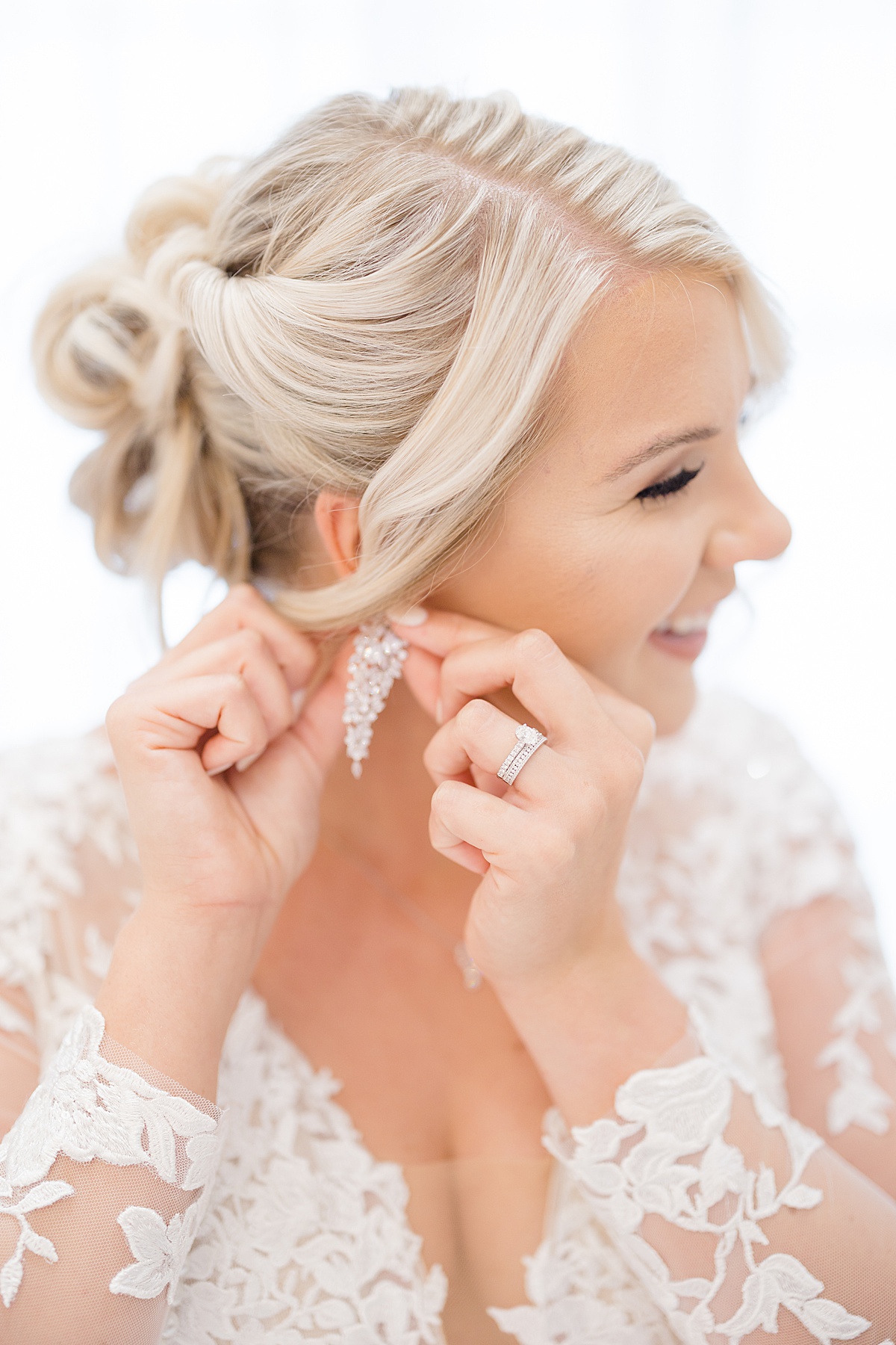 bride with elegant updo fastens dangling diamond earring before Western themed July wedding