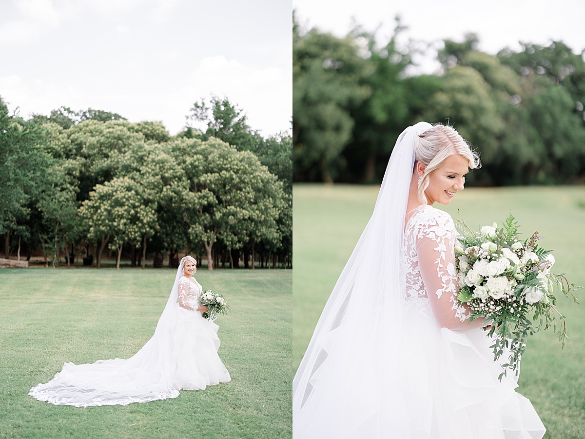 bride in romantic lace and tulle gown with white roses poses in field for Destination wedding photographer