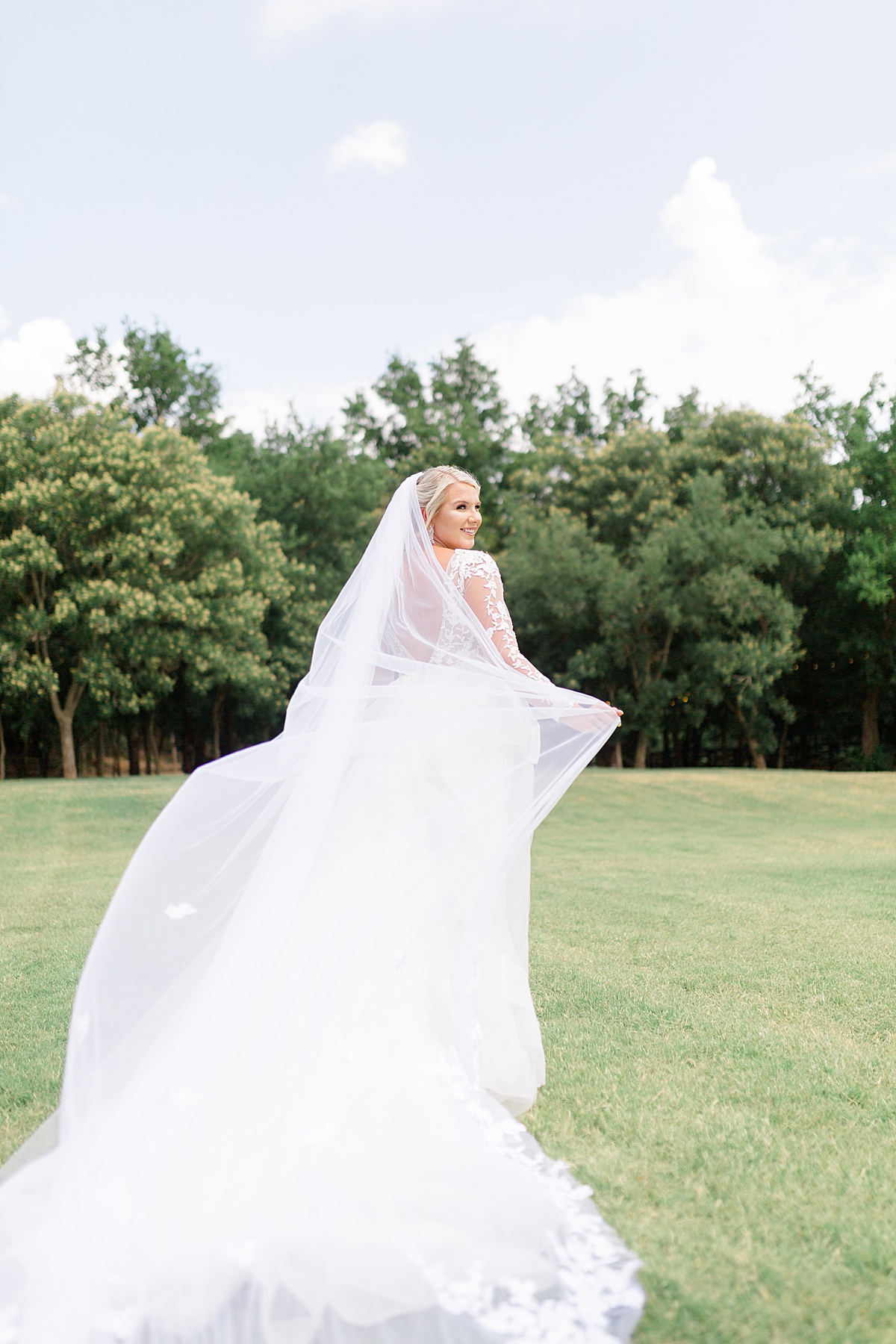 bride in romantic full length veil runs through green field before ceremony shot by Destination wedding photographer