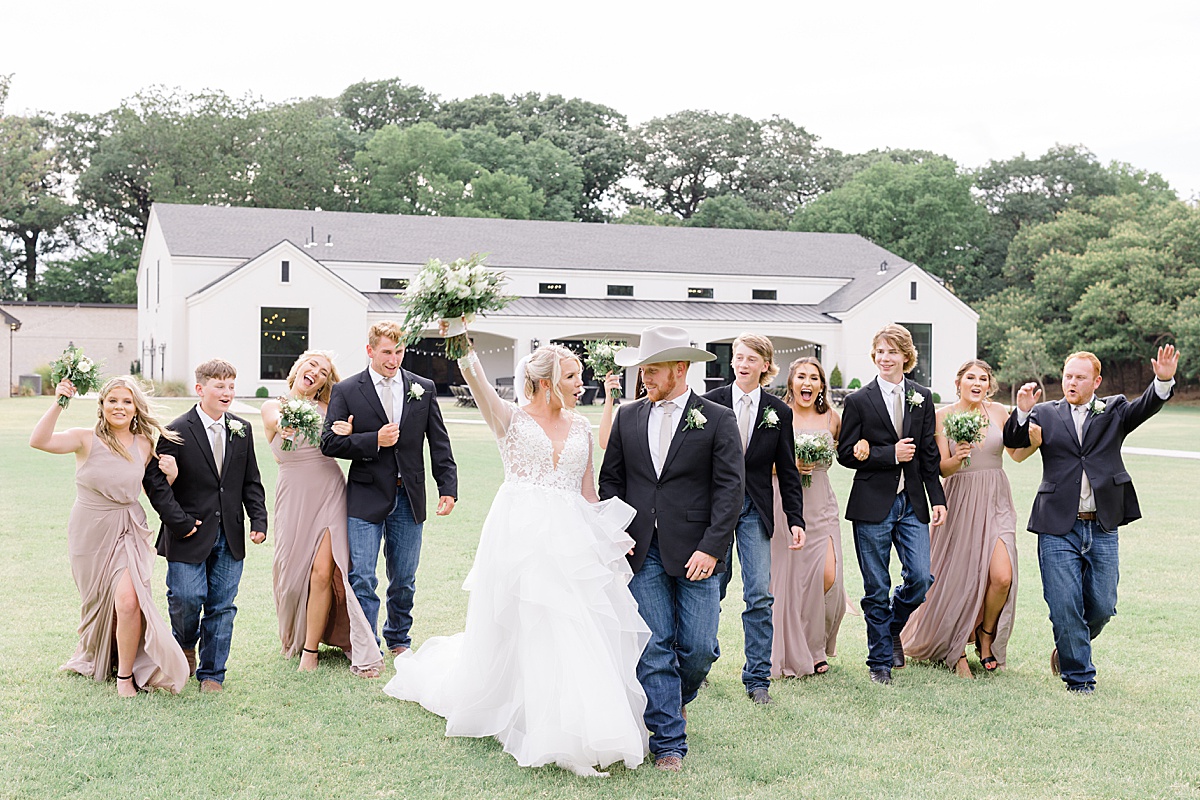 western themed bridal party walks with newlywed couple in front of modern farmhouse shot by Hunter Hennes Photography