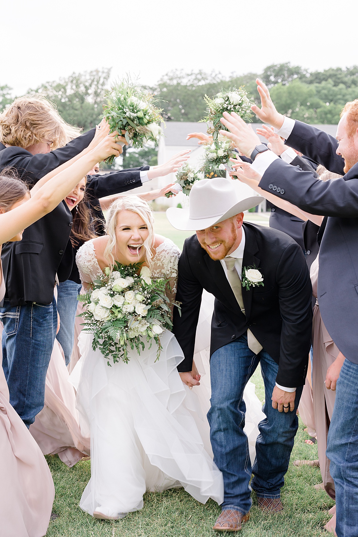 classy western bride and groom with white bouquets are celebrated by wedding party after ceremony by Hunter Hennes Photography