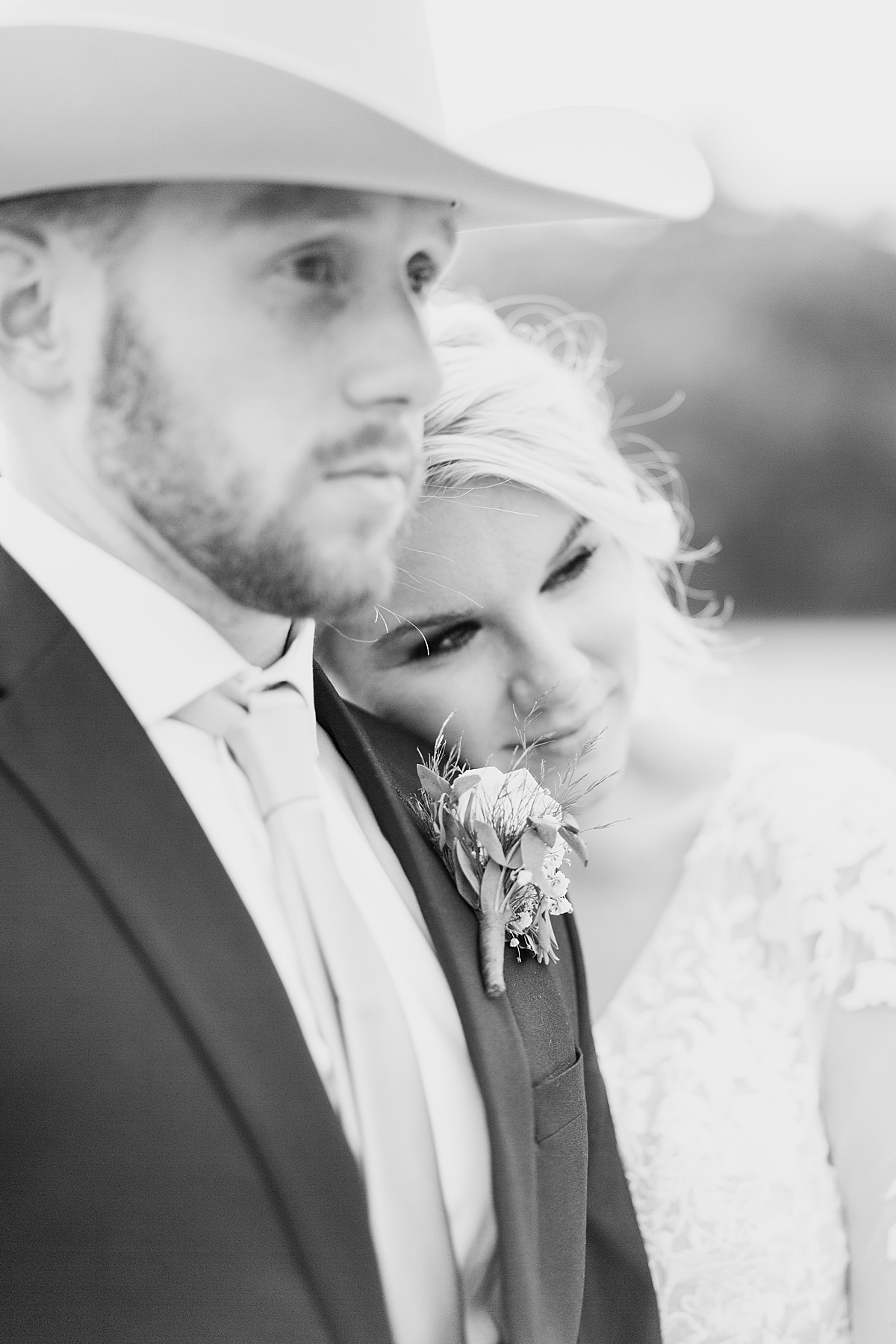 bride in romantic lace and groom with felt western hat pose with her head on his shoulder after wedding shot by Hunter Hennes Photography