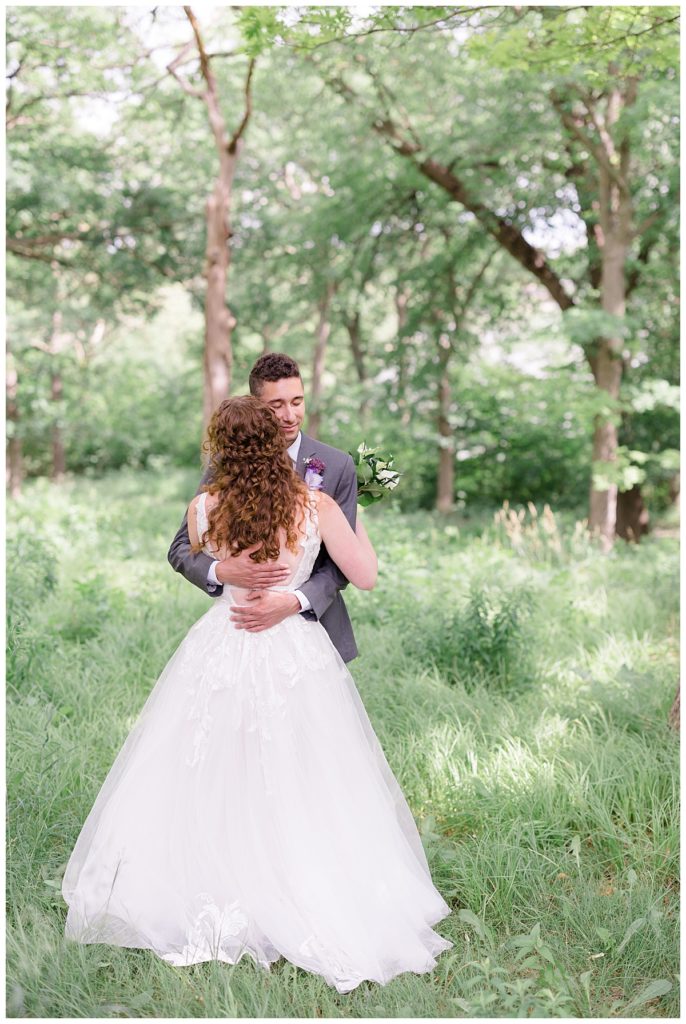 couple hugs in green meadow by destination wedding photographer