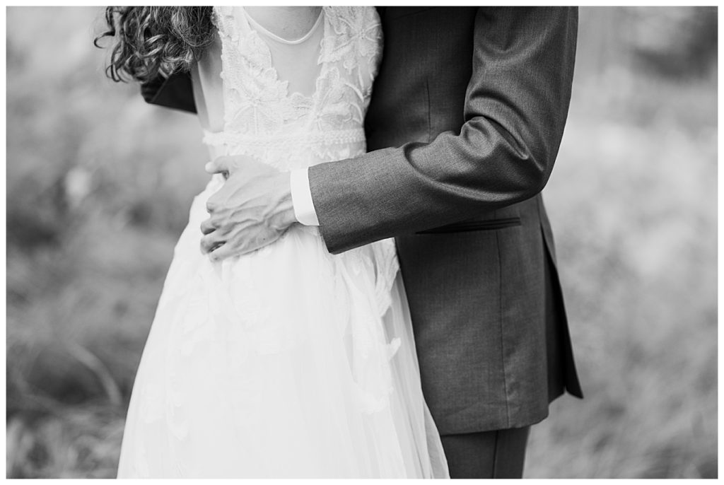 groom puts hands around bride's waist by Hunter Hennes Photography 