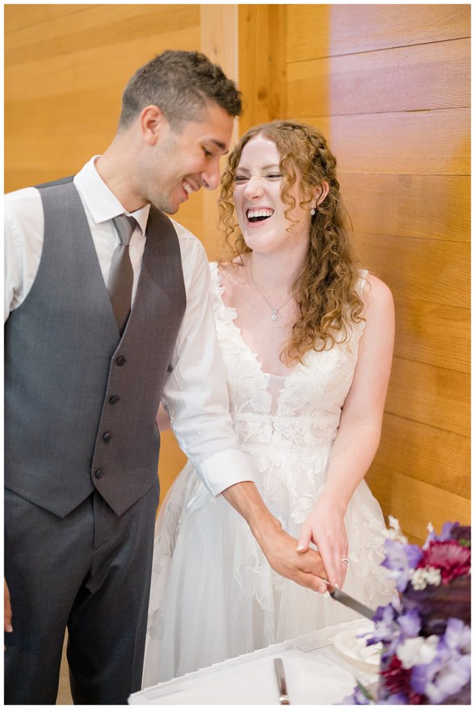 couple laughs together as they cut cake  by Hunter Hennes Photography 