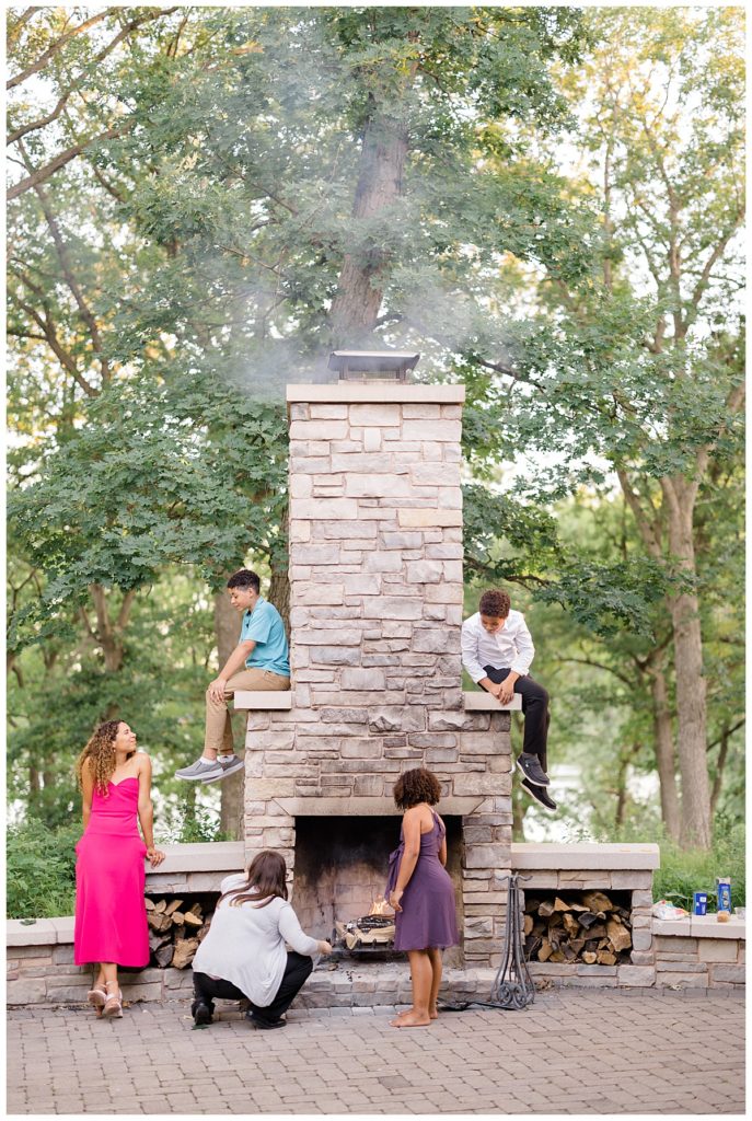 kids sit on and around chimney and firepit at Minnesota park wedding