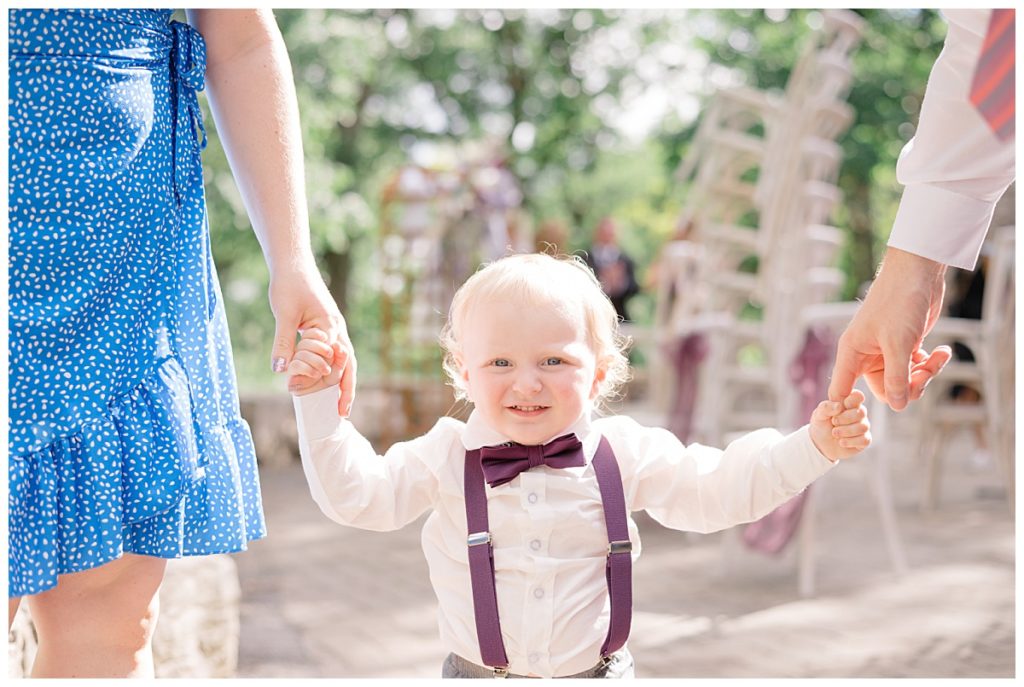 toddler holds hands of mom and dad by destination wedding photographer