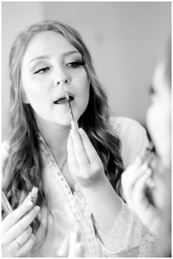 woman applies lipstick in mirror by destination wedding photographer