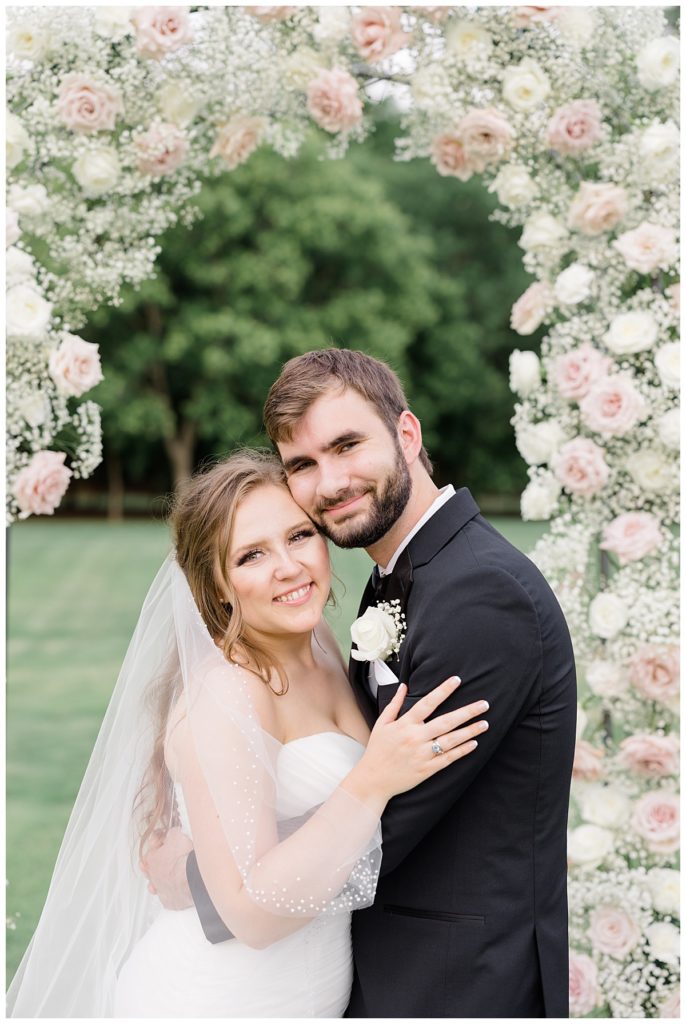 couple embraces under floral arch by Hunter Hennes