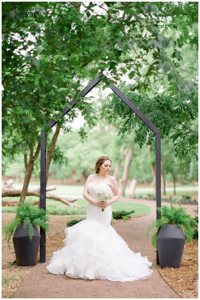 bride stands under geometric arch at romantic Oklahoma wedding