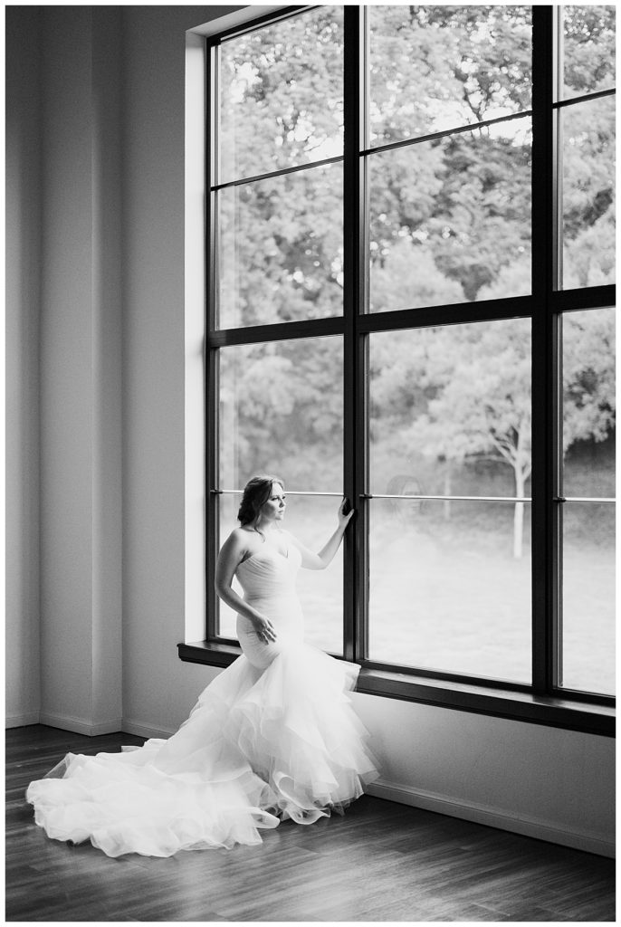woman looks out window in gown by destination wedding photographer