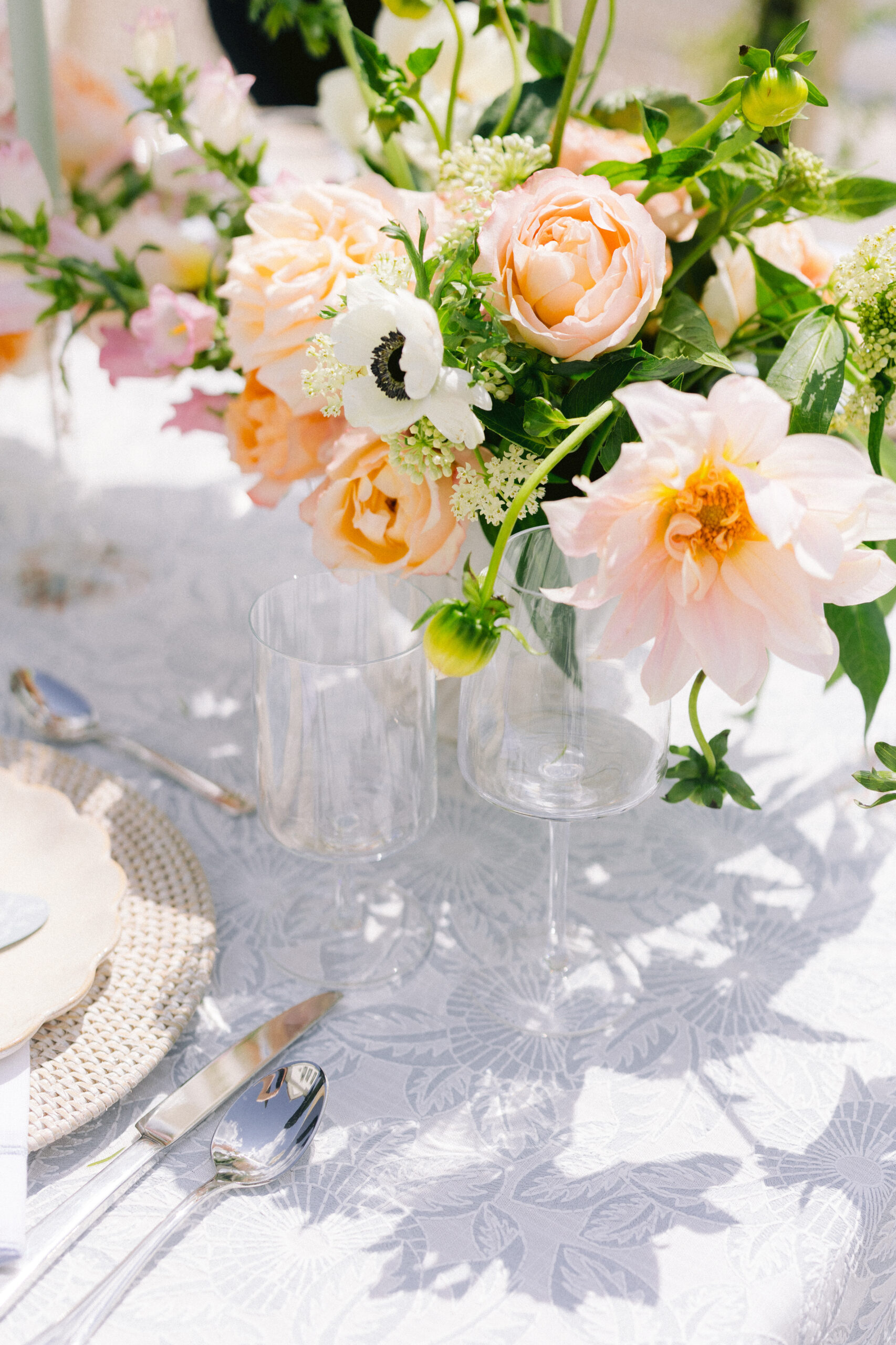 photo of wine glasses with pink and orange flowers on reception table