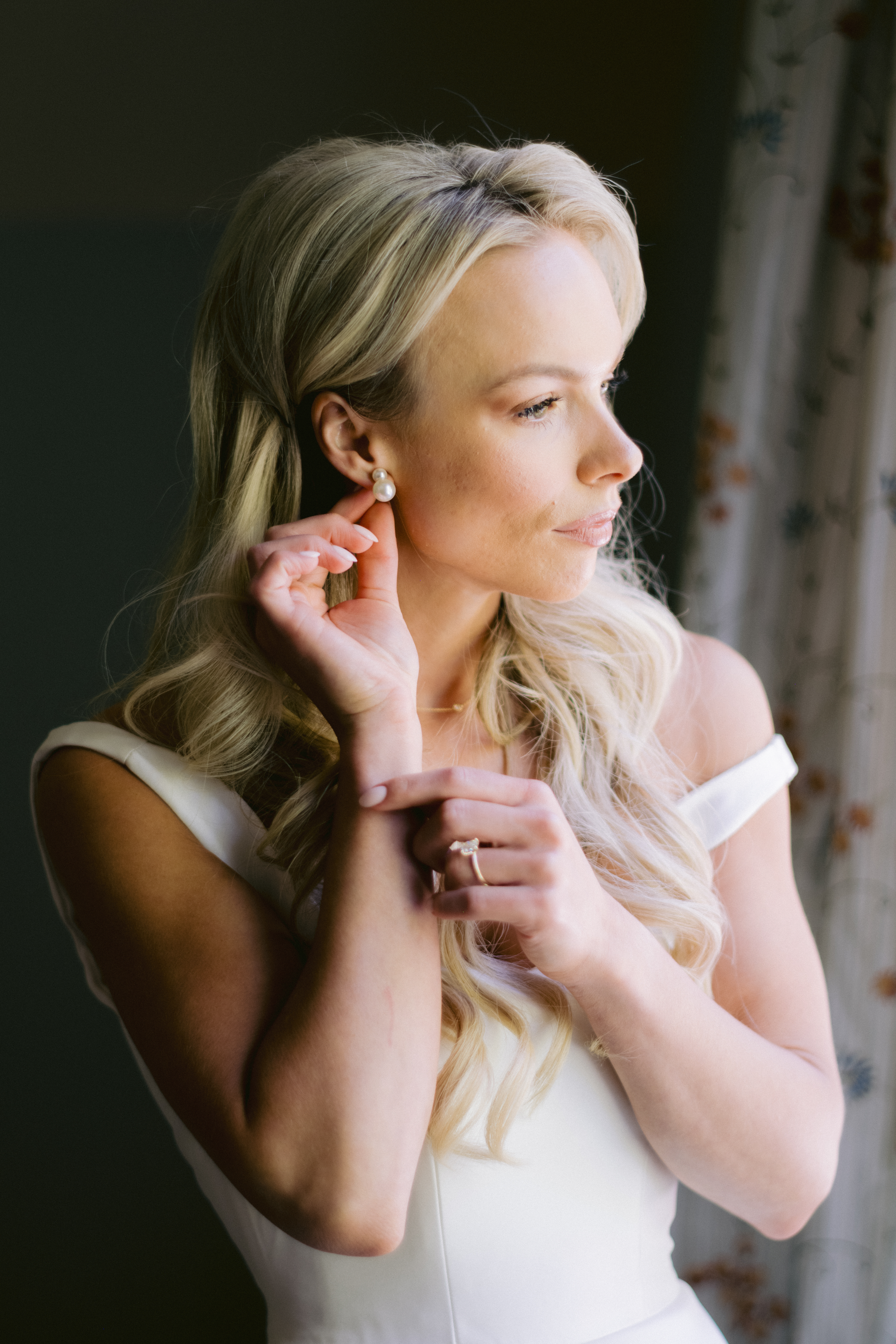 bride putting on her pearl earrings