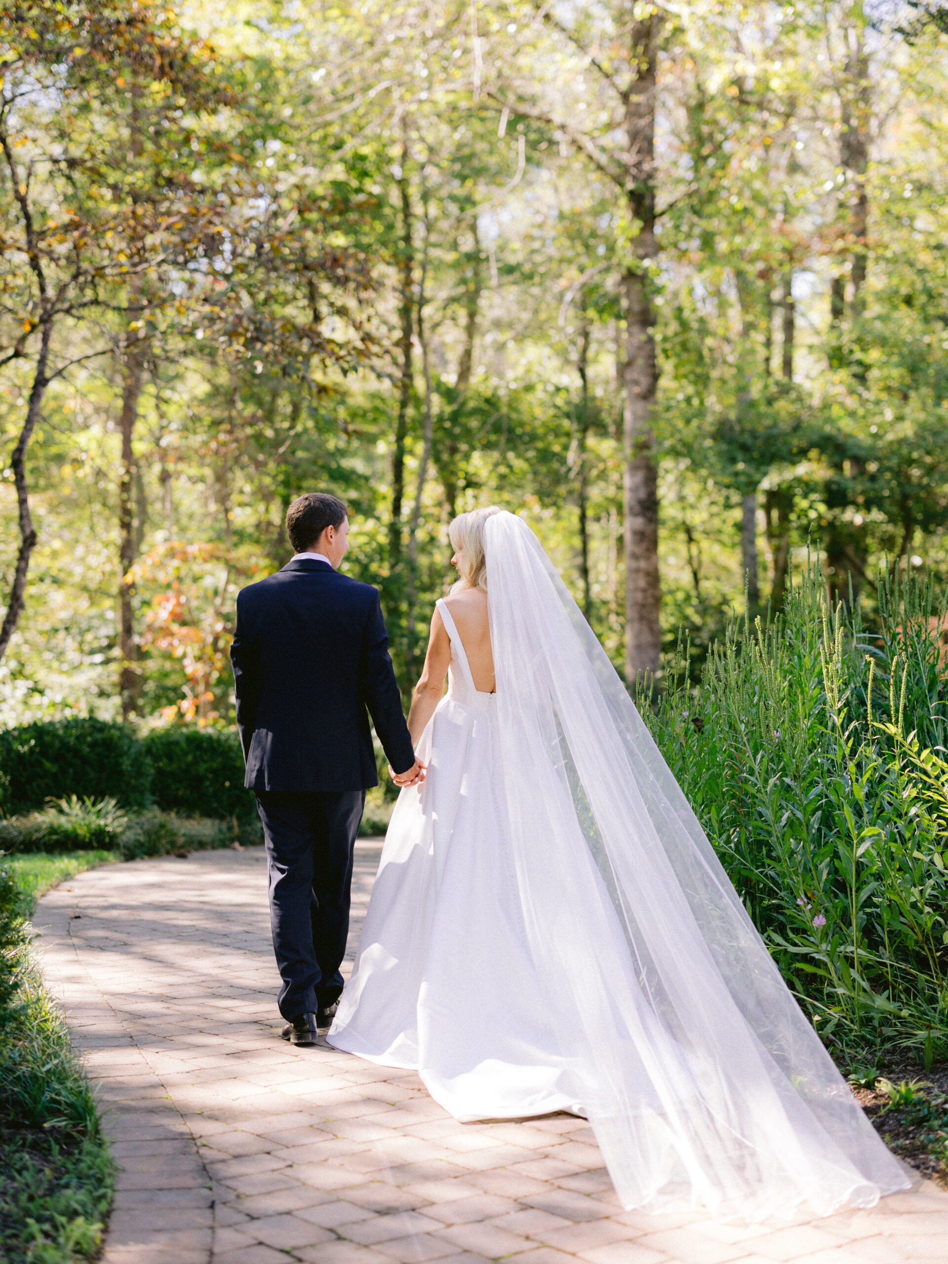 Wedding bride and groom walking away from camera hand in hand